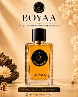 Boyaa luxury daily wear perfume bottle by Startup Aromas, elegantly presented on a golden textured surface with soft background lighting, flanked by a delicate white flower and dry floral accents.